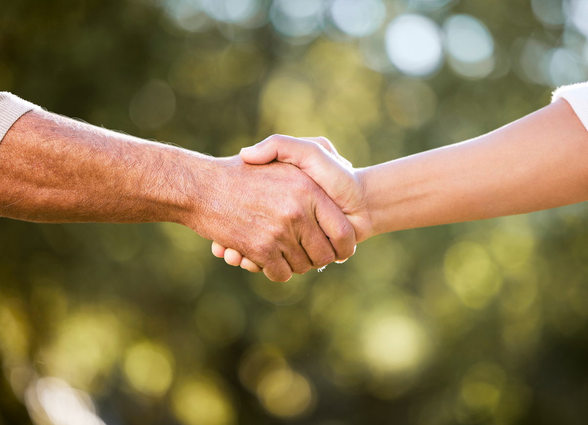 Shot of two shaking hands outdoors